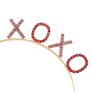 Dettaglio del cerchietto XOXO con strass rossi e rosa scintillanti su base in metallo dorato