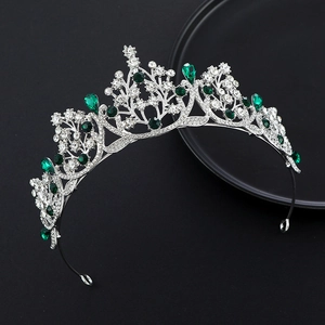 Detail of silver crown with emerald green gems and sparkling crystals in baroque style