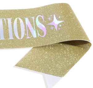 Macro shot of gold glitter sash fabric with holographic silver ions text and star motifs