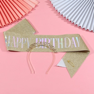 Close-up of golden glitter birthday sash and rose gold metal headband on pink backdrop