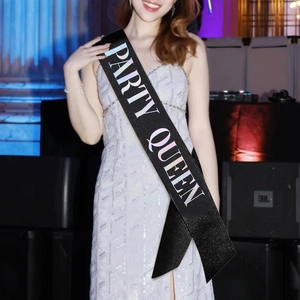 Detail of black satin Party Queen sash with holographic lettering on a sequin dress
