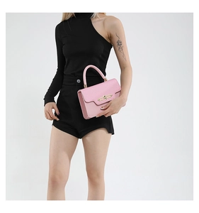 Detailed view of pink pebble grain handbag featuring a rectangular gold metal clasp lock