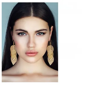 Golden hollow leaf drop earrings in Greek goddess style worn by a blonde model
