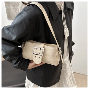 Detail of cream white faux leather shoulder bag with crocodile pattern and silver buckle