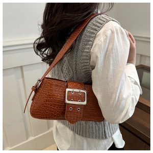 Detailed close-up of brown crocodile texture shoulder bag with large silver buckle
