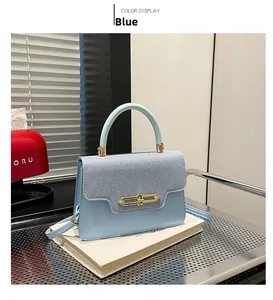Detail of blue leather and denim crossbody bag with golden U-shaped buckle closure