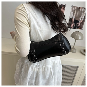 Close-up of a glossy black underarm bag featuring dual silver buckles on a leather strap