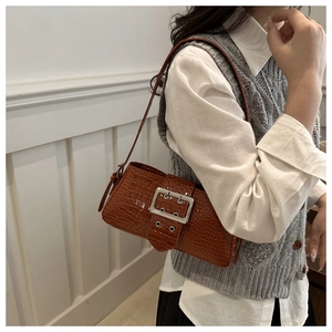 Brown crocodile embossed shoulder bag with large silver buckle on a stylish model