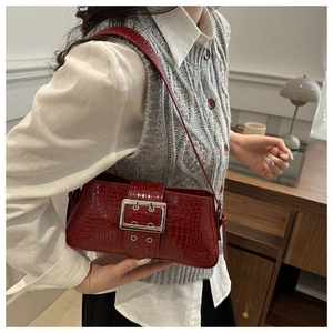 Detail of red crocodile pattern shoulder bag with large silver buckle on vintage strap