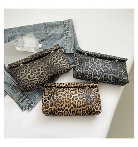 Detailed view of three leopard print clutch bags with gold snap buttons and foldover design
