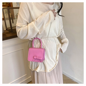Close-up of a pink mini crossbody bag with a 3D bow detail and silver chain strap