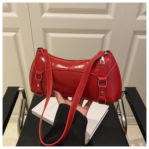 Detail of red patent leather shoulder bag with silver buckle and high-gloss finish