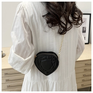 Back view of a woman wearing a black heart-shaped quilted bag with gold chain strap