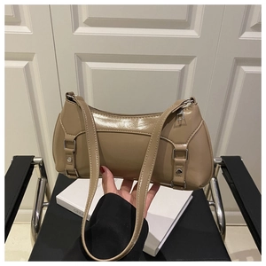 Close-up of khaki baguette shoulder bag with silver studs and buckles on a book