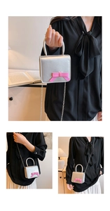 Detail view of a silver square crossbody bag featuring a pink bow and metal chain strap