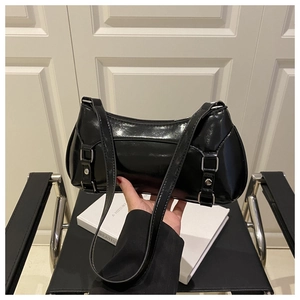 Detail of black glossy faux leather baguette bag with silver metal buckles and slim strap