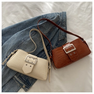 Detail of a large crocodile embossed leather shoulder bag with a silver square buckle