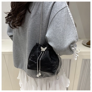 Detail of black drawstring bucket bag with silver butterfly charm and pearl beads