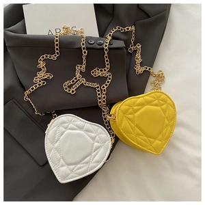 Quilted heart-shaped mini bags in white and yellow with gold chain shoulder straps