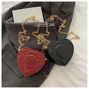 Close-up of heart-shaped quilted chain bags in red and black with gold hardware