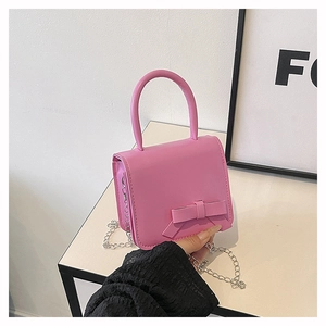 Detailed view of pink crossbody bag with a 3D bow decoration and silver metal chain strap