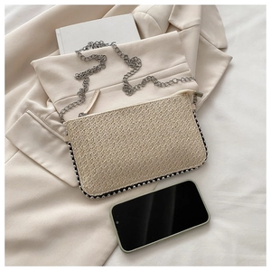Detail of beige woven crossbody bag with silver chain strap and metal bead trim