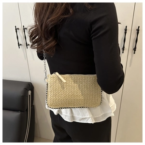 Dettaglio borsa a tracolla intrecciata beige con finiture in perline e catena in metallo