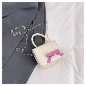 Detail of a mini cream handbag with a pink leather bow on a blazer and bed sheets