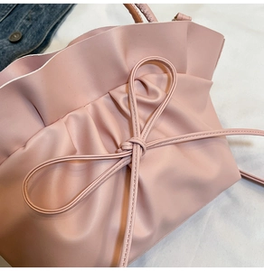 Gros plan d'un sac à main rose avec design plissé et un petit nœud décoratif élégant
