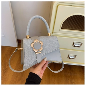 Détail du sac bandoulière bleu clair avec rabat scintillant et fermoir fleur dorée