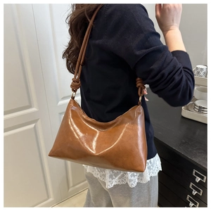 Détail du sac à bandoulière en cuir ciré marron brillant avec sangle à nœud élégante