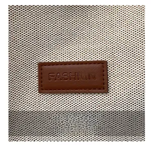 Detail of the woven canvas texture with a brown leather FASHION label patch