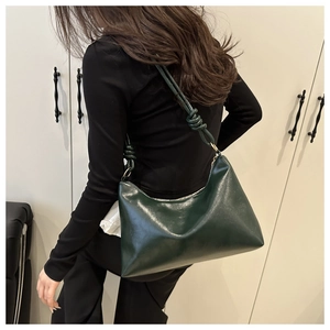 Détail du sac à bandoulière vert foncé brillant avec bandoulière nouée et anneaux en métal