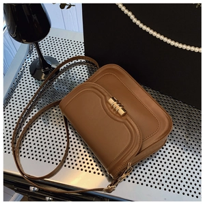 Close-up of caramel leather crossbody bag with cylindrical gold metal twist lock