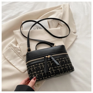 Détail du sac à main en tweed noir à carreaux avec fermetures éclair dorées