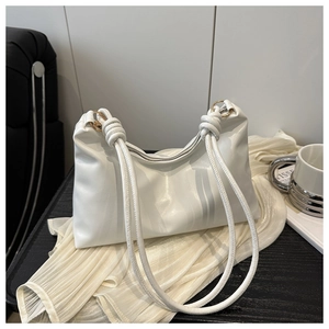 Détail du sac cabas blanc en similicuir avec bandoulière nouée sur table en bois