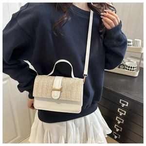 Detail of woven straw flap and gold H-buckle on a stylish white crossbody bag