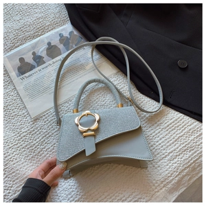 Détail du rabat scintillant et boucle fleur dorée sur sac à main gris clair