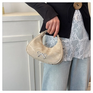 Detail of light beige saddle bag with marble pattern texture and silver bow buckle