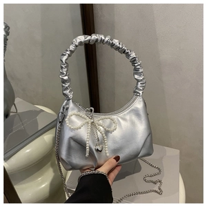 Close-up of silver metallic cloud bag with pearl bow, heart charm and scrunchie handle