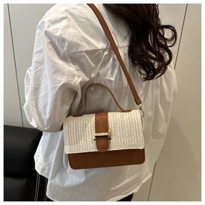 Close-up of woven patchwork crossbody bag with brown leather and gold metal buckle detail