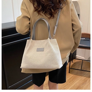Detail of canvas tote bag with fashion leather patch shown on model in modern room