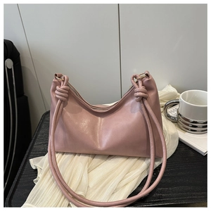 Détail du sac à bandoulière rose clair avec sangle nouée élégante et texture en cuir lisse