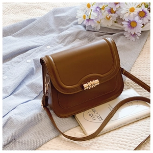 Detailed view of brown PU leather crossbody bag with cylindrical gold metal buckle closure