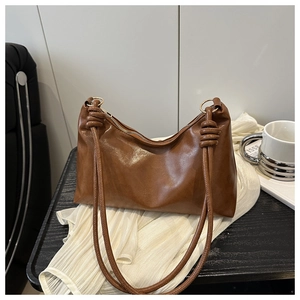 Gros plan sur la texture du cuir marron et le détail du nœud sur un sac à bandoulière