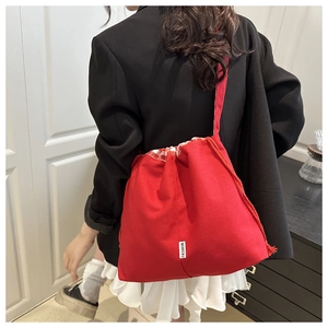 Detail of red drawstring shoulder bag featuring a white FASHION label on the side