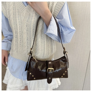 Détail du sac à bandoulière en cuir marron brillant avec rivets dorés et boucle