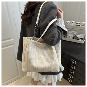 Detail of off-white straw tote bag showing V-shaped weaving and leather strap chain