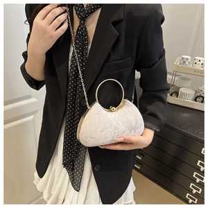 Close-up of elegant white floral lace evening bag with gold ring handle and chain strap