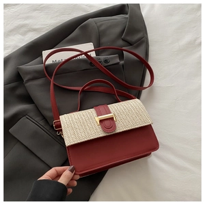 Detail of red leather and straw woven bag featuring gold clasp on grey fabric background